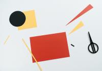 Several paper rectangles, triangles and circles beside a pair of scissors.