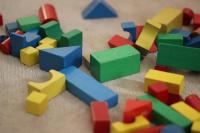 Coloured wooden blocks of different shapes and sizes are scattered over a carpet.